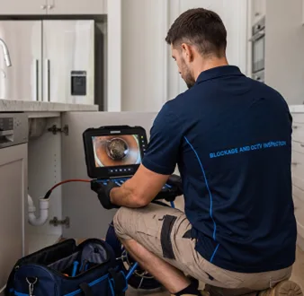 Plumber clearing a blocked toilet in a Narrabeen bathroom